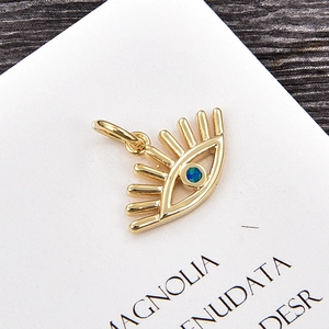 Detalle del colgante ojo del diablo dorado con piedra de ópalo azul y pestañas finas