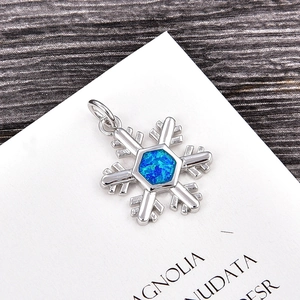 Macro view of snowflake pendant with blue opal stone inlay and silver plating