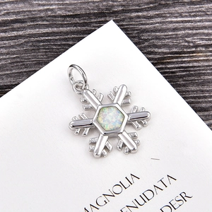 Macro shot of snowflake pendant with iridescent opal inlay on a decorative botanical card