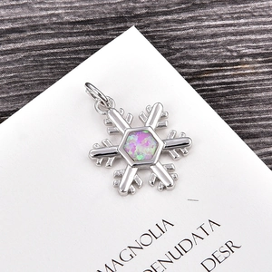 Macro view of snowflake pendant with iridescent pink opal inlay and silver finish