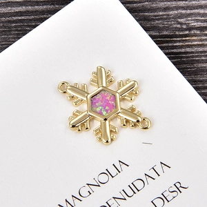Dettaglio di un ciondolo esagonale dorato con opale viola e design a fiocco di zircone
