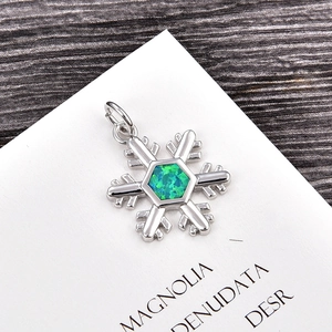 Macro view of snowflake pendant with green opal stone on dark wood background
