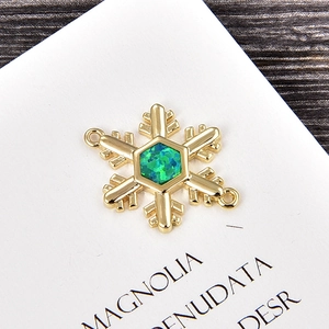 Dettaglio del ciondolo a fiocco di neve con opale verde esagonale e metallo dorato