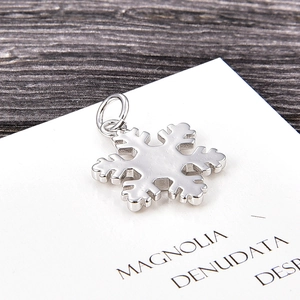 Silver snowflake pendant with metal matte texture on a white card and wooden background