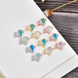 Macro detail of heart-shaped opal and zircon jewelry connectors in gold and silver plating