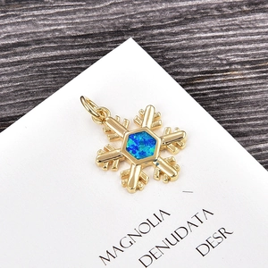 Detailed view of a gold snowflake pendant featuring a blue opal center on white card