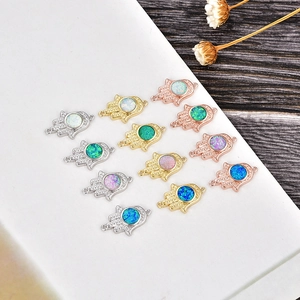 Detail of Hamsa opal charms with gold, silver and rose gold finishes on marble background