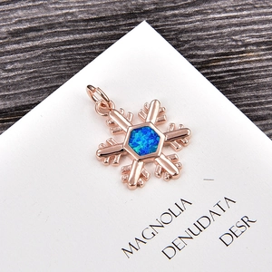 Macro view of snowflake pendant with blue opal gemstone in rose gold plating