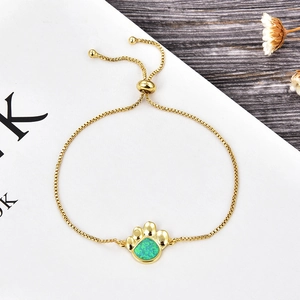 Détail du bracelet réglable en or avec pendentif patte de chien et opale verte