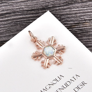 Macro detail of snowflake pendant with white opal inlay and rose gold finish plating