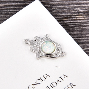 Macro detail of Hamsa Hand connector with white opal and cubic zirconia inlay