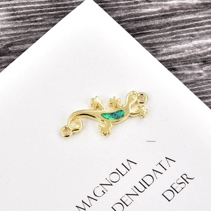 Macro detail of a golden lizard pendant with green opal inlay and dual circular rings