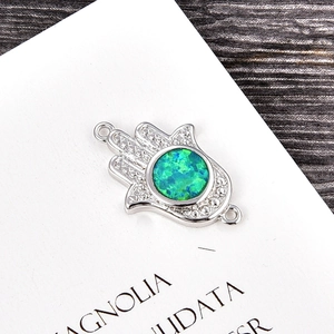 Macro view of Hamsa Hand connector charm with green opal inlay for jewelry making