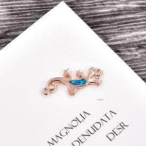Macro view of rose gold gecko connector with blue opal inlay on white card display