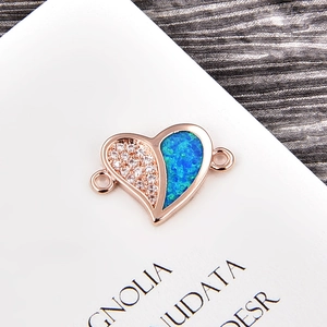 Detailed shot of a rose gold heart charm connector with blue opal and white zircons