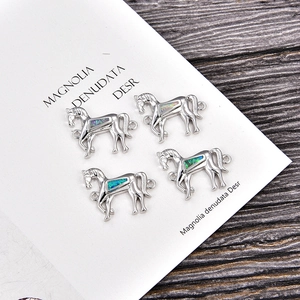 Set mit vier silbernen Pferdependeln mit Opal-Inlay für DIY-Schmuck auf Holzoberfläche