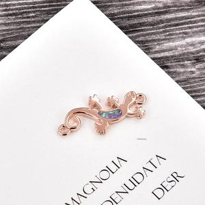 Detail of rose gold gecko lizard pendant with colorful opal stones and dual ring connectors
