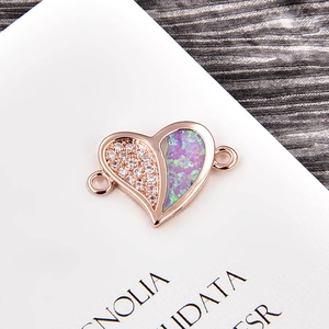 Macro detail of heart-shaped rose gold charm with pavé cubic zirconia and opal inlay
