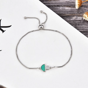 Détail du bracelet en argent avec opale verte et pendentif en zircon sur plaque blanche