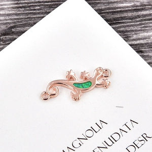 Macro view of rose gold gecko pendant featuring green opal inlay and dual loop rings
