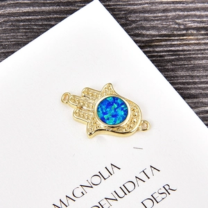 Close-up of golden Hamsa Hand charm with blue opal inlay and detailed grain texture