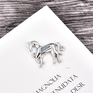 Makro-Detail von silbernem Pferdeanhänger mit blauem Opal-Inlay und Doppelschlaufe