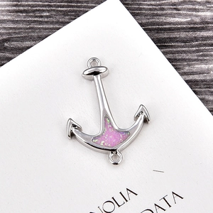 Macro view of silver anchor charm with pink opal inlay and dual link rings for bracelets