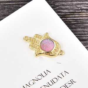 Detailed view of a gold Hamsa hand connector with purple opal stone for DIY jewelry