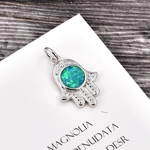 Macro shot of Hamsa hand pendant with blue fire opal inlay and dot detailing