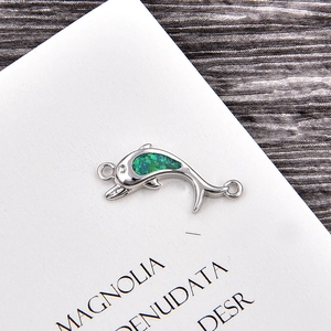 Detail of silver dolphin charm with blue-green opal inlay and double loops for bracelets