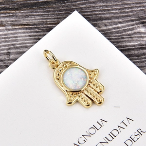 Detailed view of a golden Hamsa Hand pendant featuring a white opal stone inlay