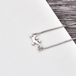 Detail shot of a silver gecko pendant necklace with opal accents on a box chain
