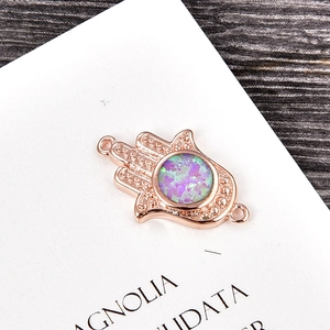 Macro shot of rose gold Hamsa Hand charm with vibrant purple opal and side connector loops