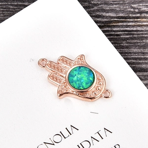 Detailed view of a rose gold Hamsa hand charm with a blue opal stone for DIY jewelry