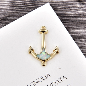 Macro detail of a gold-plated anchor pendant with a white opal stone for DIY jewelry