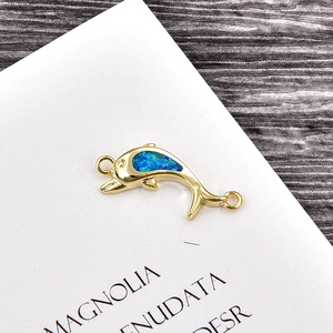Close-up of a gold dolphin charm with inlaid blue opal and zirconia for DIY jewelry
