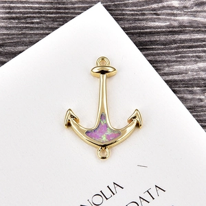Detail of a gold anchor charm with pink opal stone and dual loops for DIY jewelry