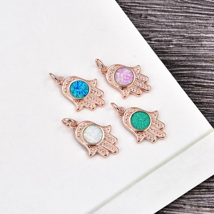 Detailed close-up of rose gold Hamsa Hand pendants with colorful opal stone inlays