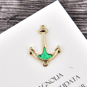 Macro shot of anchor charm with gold plating and green opal inlay for DIY jewelry