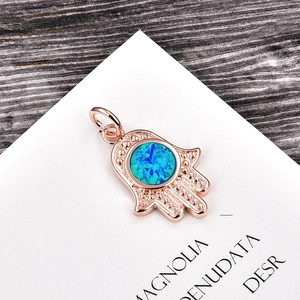 Macro view of rose gold Hamsa hand pendant with inlaid blue opal gemstone detail