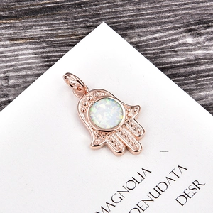 Macro view of rose gold Hamsa pendant featuring a white opal inlay and grain detail