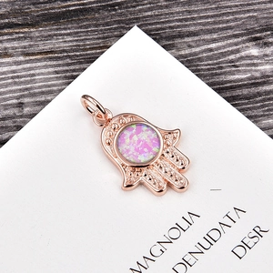 Close-up of rose gold Hamsa Hand pendant with purple opal and beaded texture