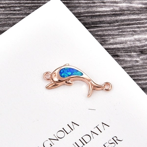 Macro detail of rose gold dolphin charm with inlaid blue-green opal for jewelry making