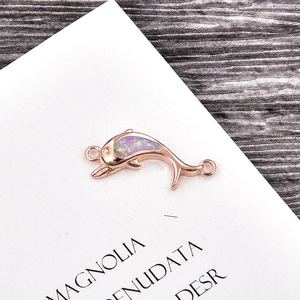 Macro detail of rose gold dolphin pendant with purple opal inlay and circular ring connectors