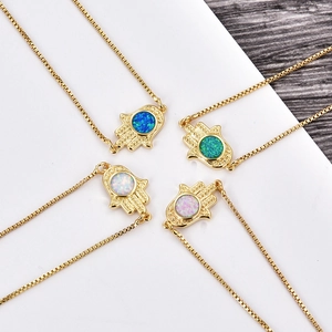 Close-up of Hamsa Hand pendants with colorful opal stones on gold box chains