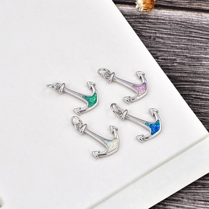 Detail view of silver anchor pendants featuring colorful inlaid opal stones and top bail rings