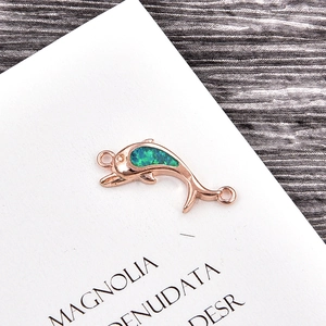 Detail of rose gold dolphin pendant with green opal stone on white art card background