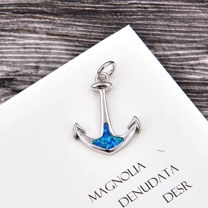 Macro shot of anchor charm pendant with blue opal stone and polished silver finish