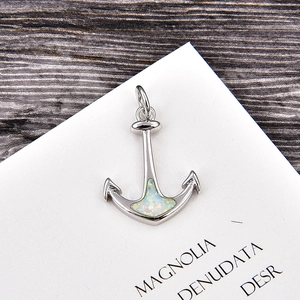 Macro detail of silver anchor pendant with opal inlay and cubic zirconia accents