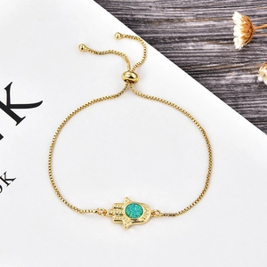 Close-up of golden Hamsa Hand bracelet with adjustable chain and turquoise opal